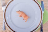 Plastikschwein auf Teller samt Besteck