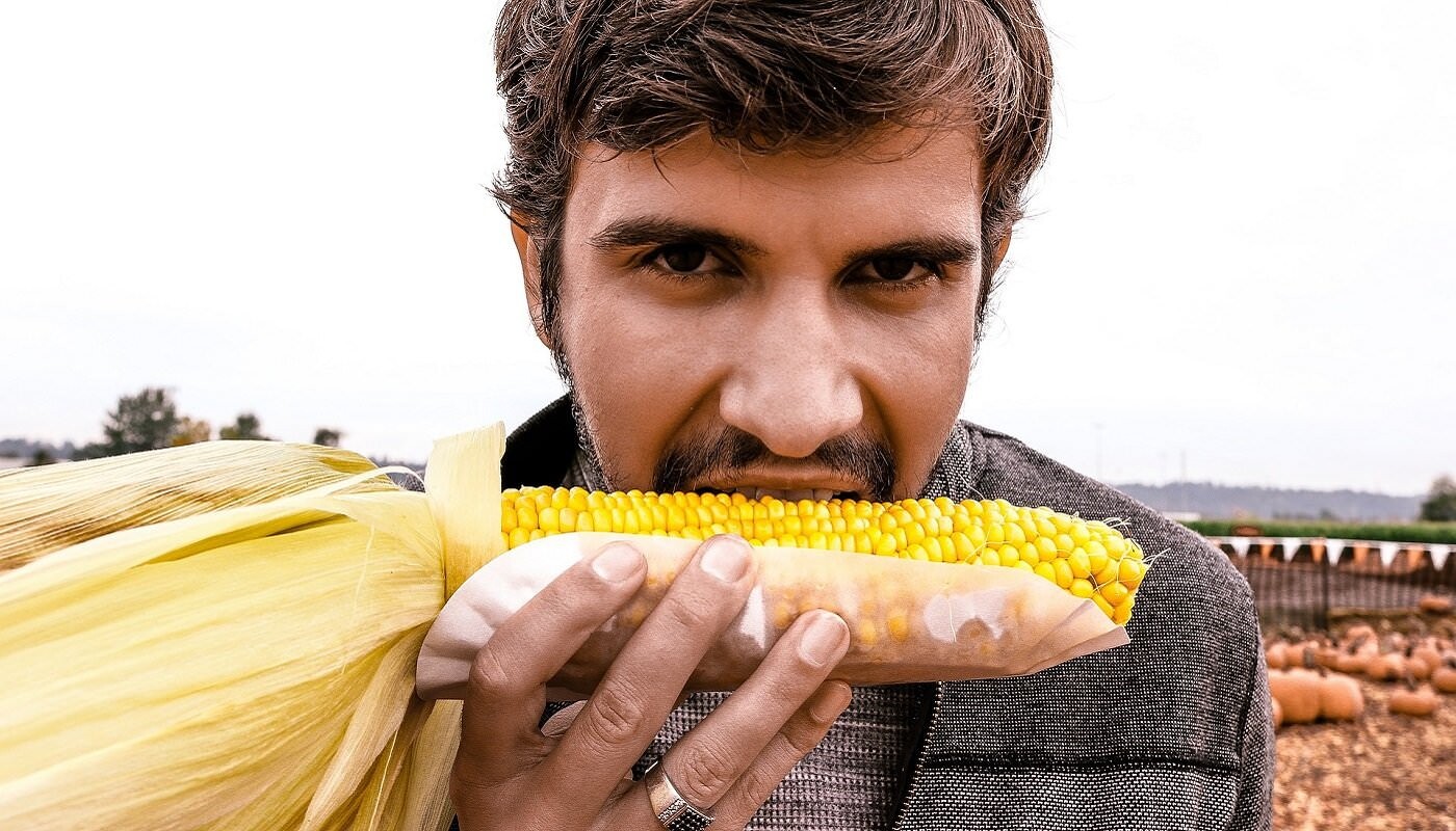 Mann beisst in Maiskolben; veganes Essen