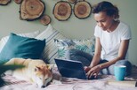 Frau mit Laptop und Hund zuhause.