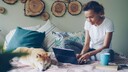 Frau mit Laptop und Hund zuhause.