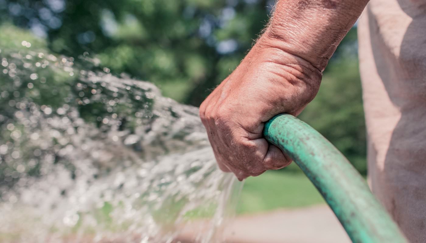 Hand hält Wasserschlauch